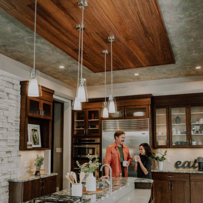 Walnut acoustic wood planks featured on a kitchen ceiling and a couple enjoying coffee together.